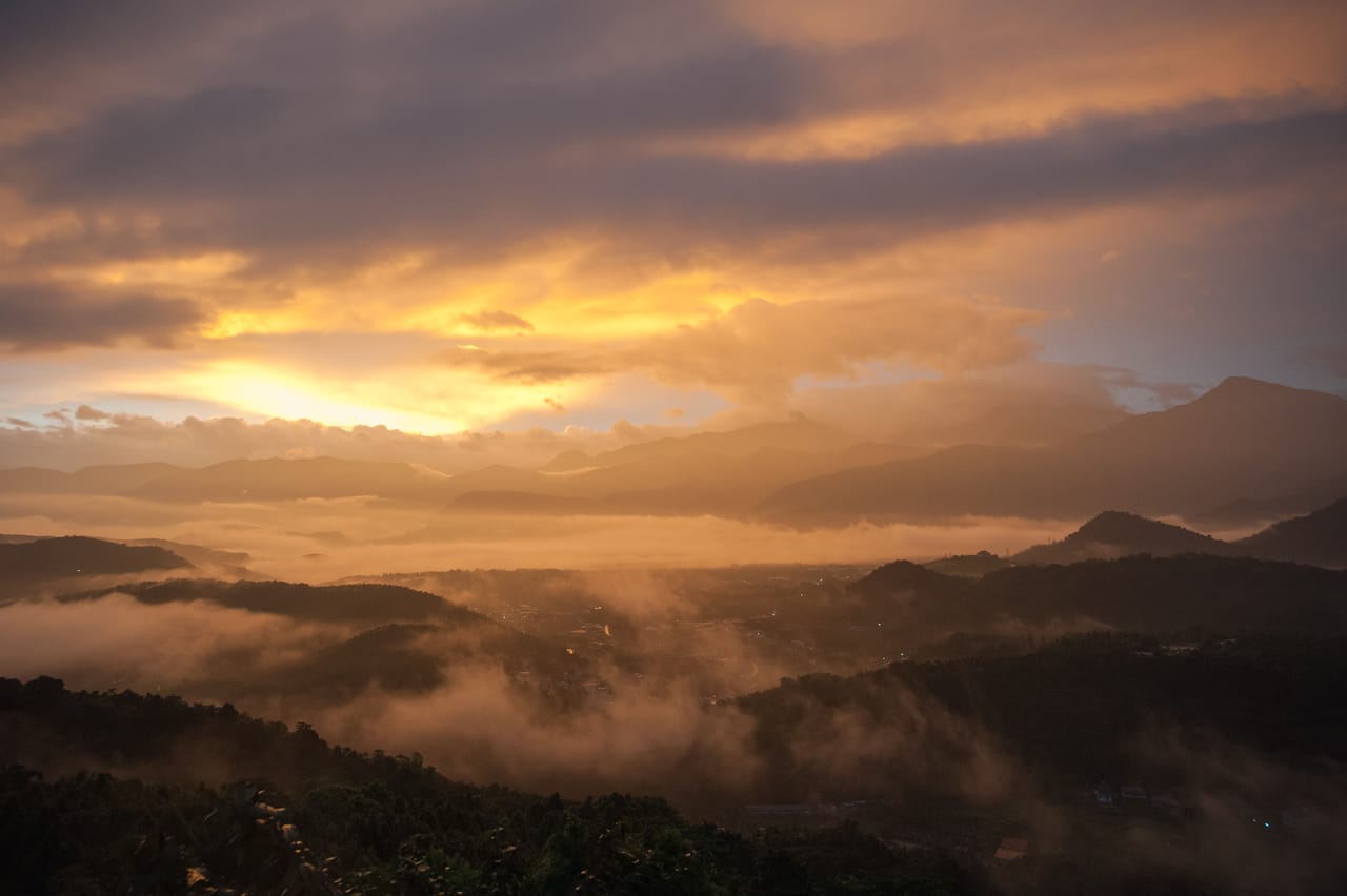 A sea of clouds at sunrise, golden light breaking through as mist moves in the valley.